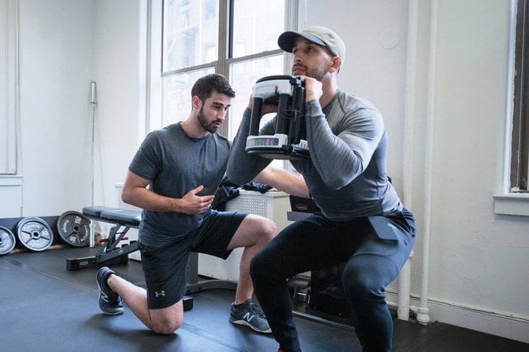 Physical therapist coaching an athlete through a strengthening exercise